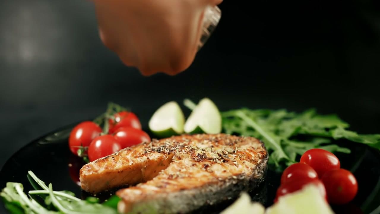 A salmon steak seasoned on a black plate